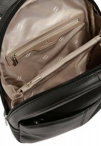 Wnętrze czarnego skórzanego plecaka z beżową podszewką, jedną kieszenią na zamek oraz wieloma kieszeniami wsuwanymi w geometryczny wzór.