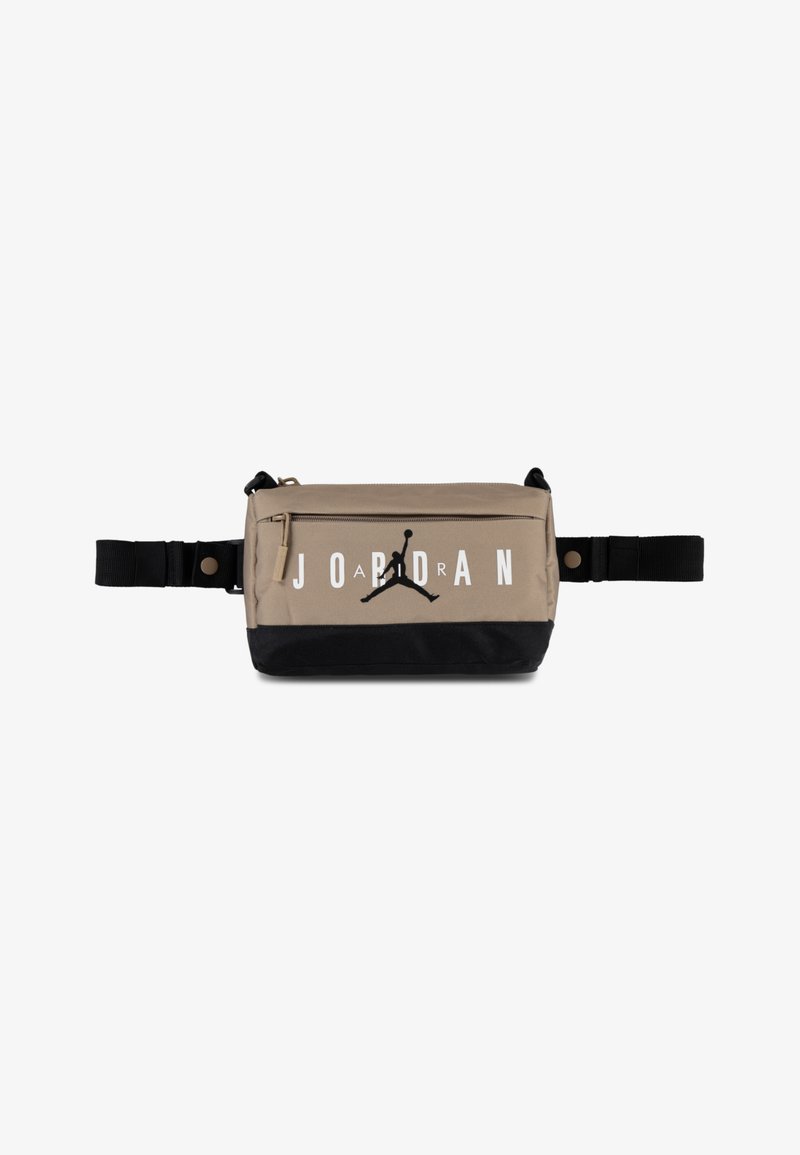 Sac en nylon beige avec un fond noir, grand texte blanc "JORDAN" et un logo Jumpman noir. Il comporte une poche zippée et des sangles réglables.