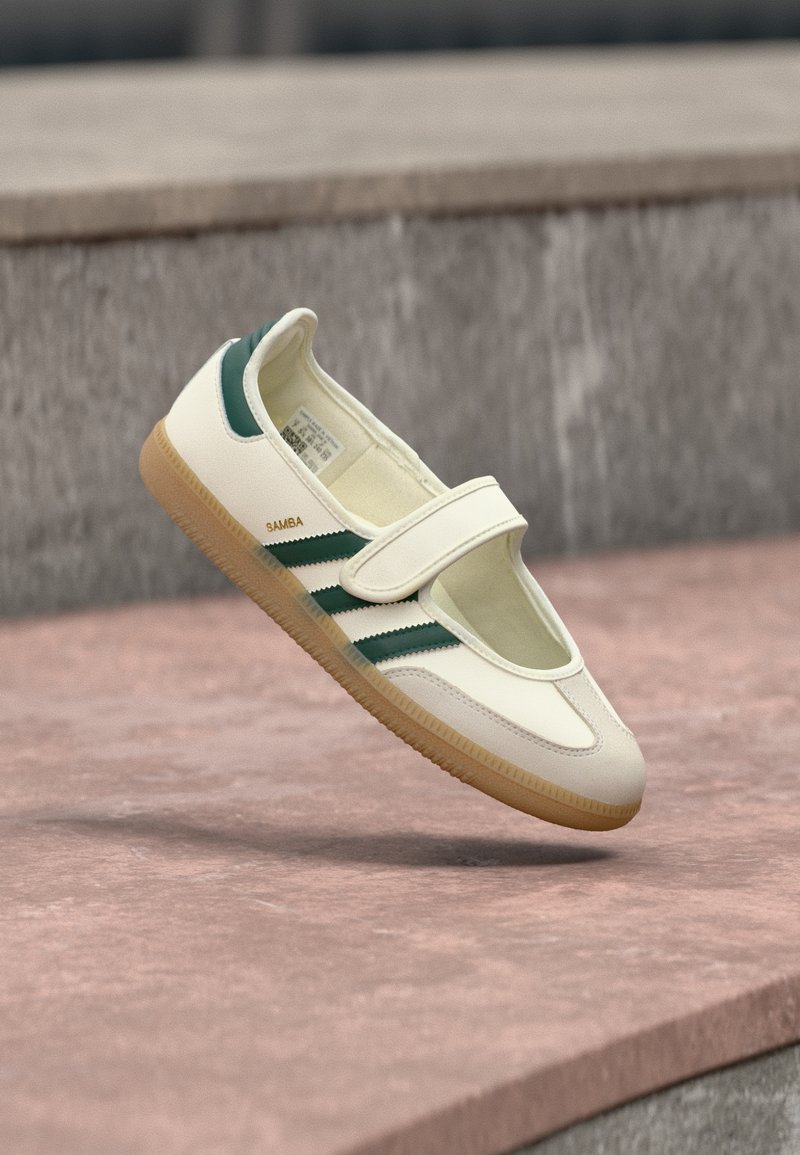 Λευκό δερμάτινο παπούτσι με πράσινες ρίγες, στρογγυλή μύτη, ασφαλισμένο με λουράκι. Σόλα από καουτσούκ, μινιμαλιστικός σχεδιασμός, ανάγλυφη ραφή κατά μήκος των επάνω άκρων.