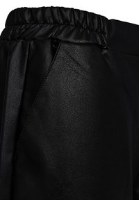 Zwarte nepleren broek met elastische tailleband en details van zijnaadzakken, met een gestructureerd oppervlak en matte afwerking.