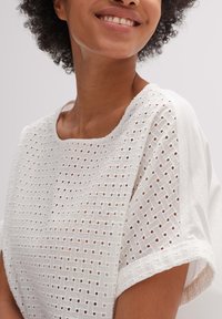 Witte top met een losse pasvorm, voorzien van textuur en geweven patronen. Ronde halslijn en korte mouwen met een gladde afwerking.