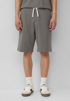 Grijze katoenen shorts met een elastische tailleband, zijzakken en een relaxte fit. Draag ze met witte sokken en beige sneakers.