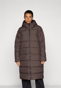 Brun pufferjakke med hette, med en quiltet design, frontglidelås, sidelommer og elastiske ermer, som går til midt på leggen.