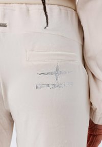 Beige sweatpants met een zachte textuur, met een achterzak en een logo-ontwerp versierd met strass op de rechterkant.