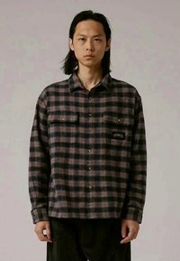 Rutig flanellskjorta i mörkblå och bruna toner, med knäppning framtill, två bröstfickor och broderad detalj på den vänstra fickan.