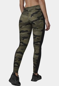 Camouflage leggings in green and black with a textured fabric and slim-fit design, featuring a solid black side panel and ankle length.
