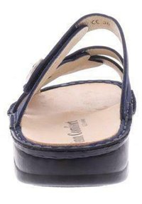 Navy blue sandals with a cork footbed, featuring two curved straps, smooth texture, and a slight platform heel. Subtle stitching detail visible.