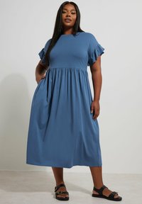 Niebieska sukienka do kolan wykonana z miękkiego materiału. Posiada krótkie, falbaniaste rękawy, okrągły dekolt oraz boczne kieszenie z marszczonym pasem.
