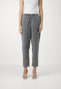 Sive hlače z elastičnim pasom, ohlapnega kroja, ravnih hlačnic in mehkega tekstila, podobnega denimu. Ujemajo se z belimi sandali na trak.