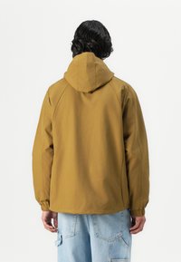 Brun hættetrøje med en afslappet pasform, elastiske manchetter og en glat tekstur. Bagsiden viser sømdetaljer og et enkelt design.