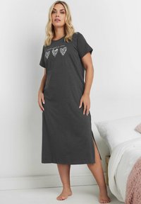 Grå bomulls-nattklänning med korta ärmar, prydd med tre hjärtmotiv i vitt. Sidoveckar för ökad rörlighet. Golvlång design.