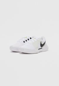 Weiße Sportschuhe mit Mesh-Obermaterial, schwarzen Akzenten und limettengrünen Details. Verfügt über eine strukturierte Sohle und ein kontrastierendes Nike-Logo.