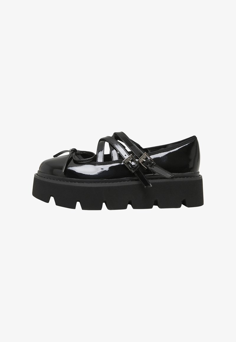 Chaussure Mary Jane en cuir verni noir avec semelle épaisse rainurée, brides à double boucle et petit nœud décoratif sur l'embout arrondi.