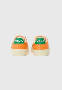 Sneakers arancioni con logo "VEJA" verde sul retro, con una suola chiara e texture liscia. Design semplice e classico.