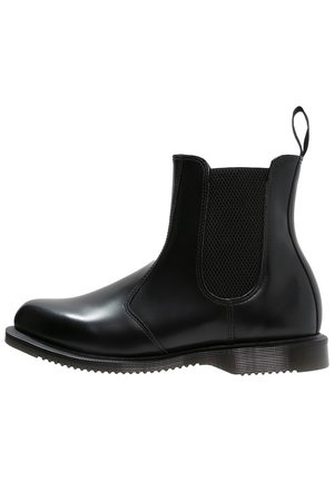 Bottine Chelsea noire avec panneau latéral élastique, languette à l’arrière et semelle basse rainurée.