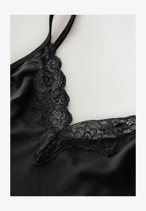 Zwarte top met een delicate kantafwerking langs de V-vormige halslijn en smalle verstelbare bandjes, gemaakt van een gladde satijnen stof.