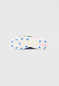 Μονάδα σόλας αθλητικού παπουτσιού ασπρόμαυρη με μπλε και ροζ λεπτομέρειες. Διαθέτει κυκλικά καρφιά για πρόσφυση και λεία, υφή επιφάνεια.