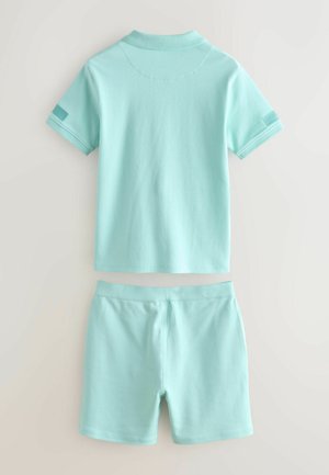 Vedere din spate a unui set pentru copii format dintr-un tricou polo cu mânecă scurtă, de culoare turcoaz deschis, și pantaloni scurți asortați, pe un fundal simplu.