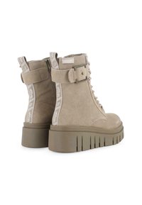 Botines de ante beige con suela de plataforma gruesa, cordones en la parte delantera, cremallera lateral y detalles de tela con la marca en el tacón.