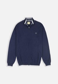 Cardigan zippé marine, en matière tricotée, col côtelé avec rayures blanches, manches longues et logo discret près de la poitrine.