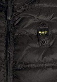 Czarna ocieplana kamizelka o gładkiej fakturze, z zapięciem na zamek z przodu oraz prostokątną żółto-czarną metką z napisem "Blauer U.S.A."