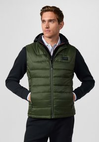 Kamizelka puchowa w ciemnozielonym kolorze, z zamkiem z przodu, poziomymi przeszyciami i czarnymi rękawami. Zawiera naszywkę z logo na klatce piersiowej.