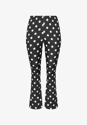 Pantalones negros ajustados con lunares blancos y un ligero vuelo en la parte inferior.