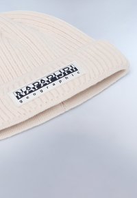Berretto lavorato a maglia rosa chiaro con una texture a coste e un'etichetta rettangolare bianca con la scritta "NAPAPIJRI" in gr assetta nera.