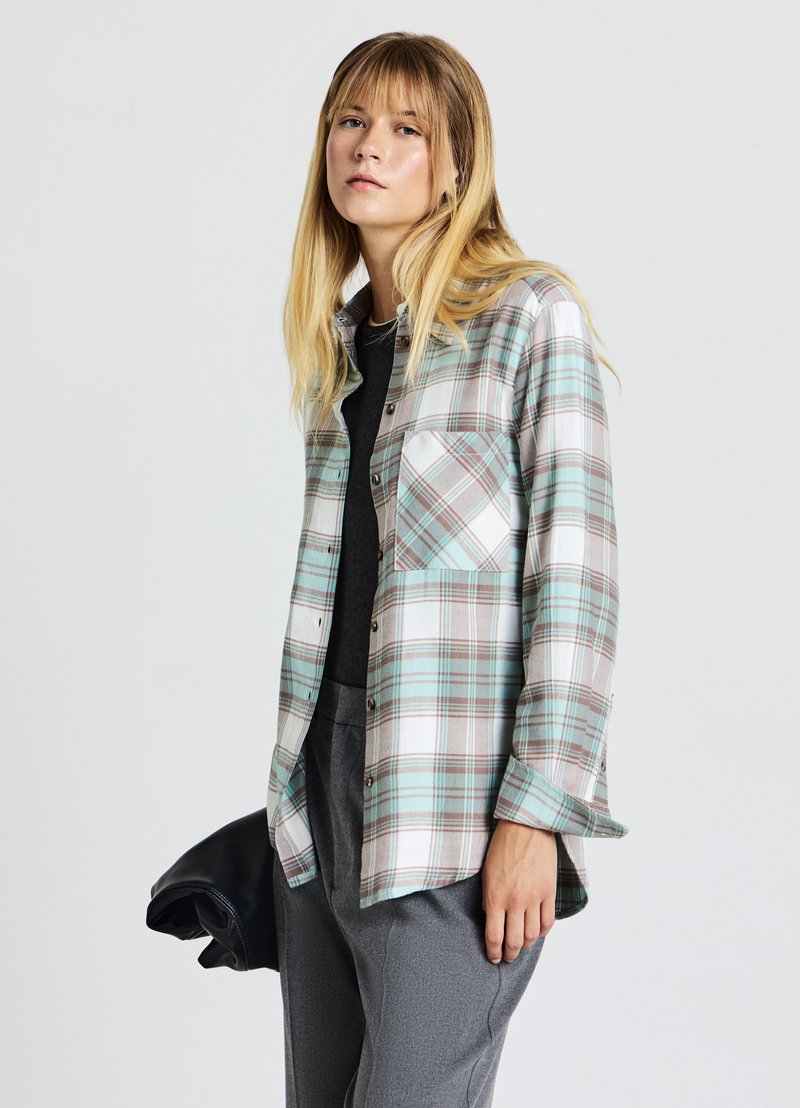 Camicia a quadri in blu chiaro, marrone e bianco. Maniche lunghe, design con bottoni a tutta lunghezza e taschino sul petto. Tessuto morbido e leggero.