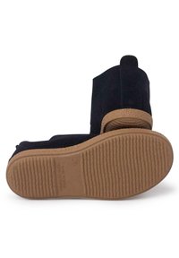 Schwarze Wildleder-Ankle-Boots mit einer strukturierten beigen Gummisohle, runder Zehenform und einer Schlaufe an der Rückseite für ein einfaches Anziehen.