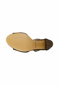 Vue de la semelle d’une chaussure à talon marron avec une semelle beige texturée et une pointe de talon noire, marquée "wojas" près de la zone de la voûte plantaire.