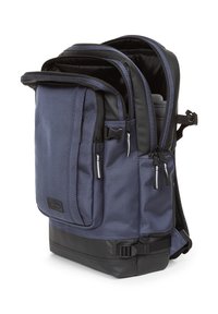 Mochila azul marino con tejido texturizado, múltiples compartimentos con cremallera, fondo reforzado negro, correas ajustables y interior acolchado.