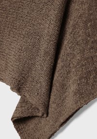 Smeđa pletena tkanina s labavim, teksturiranim tkanjem i vidljivim petljama, prikazana presavijena na bijeloj pozadini.