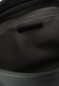 Intérieur d'un sac en cuir noir texturé avec une doublure en tissu gris et une poche zippée le long du bord supérieur.