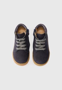 Chaussures pour tout-petits en suede bleu marine avec semelles en caoutchouc, lacets à motifs et doublure en tissu à carreaux, vues de dessus sur un fond blanc.