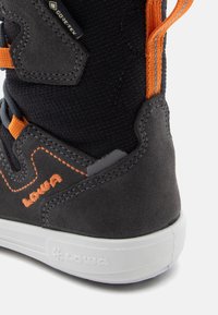 Black suede hiking boot with orange accents, textured fabric, contrasting stitching, cushioned collar, and white rubber sole with branding.