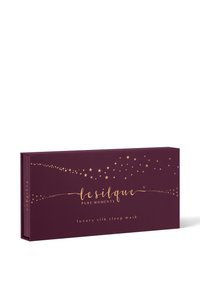 Boîte rectangulaire violet foncé avec des motifs d'étoiles dorées, étiquetée "le silque pure moments luxury silk sleep mask" sur le devant.