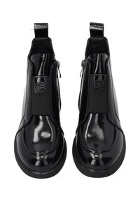 Czarne błyszczące skórzane botki za kostkę z suwakami po bokach, elastycznymi panelami, okrągłymi noskami i pętelkami z tyłu, wyeksponowane z góry na białym tle.