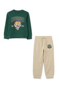 Groene sweatshirt met "CHICAGO 1982" en tijgerafbeelding, gecombineerd met beige sweatpants met een "Chicago University Athletics" logo.