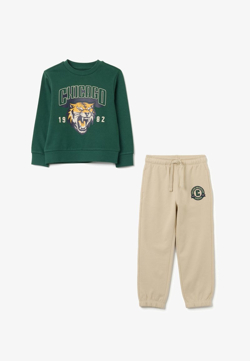 Groene sweatshirt met "CHICAGO 1982" en tijgerafbeelding, gecombineerd met beige sweatpants met een "Chicago University Athletics" logo.