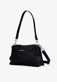Bolso de cuero negro de grano con herrajes en tono dorado, correa ajustable y logotipo de la marca en relieve, que presenta una forma rectangular y una textura suave.