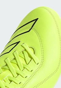 Scarpino da calcio giallo neon con tomaia sintetica testurizzata, cuciture nere e lacci piatti, progettato per offrire prestazioni ottimali sul campo.