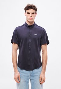 Lühikeste varrukatega tumesinine puuvillast särk, millel on nööpidega kinnitatav krae ja väike valge "BOSS" logo rinnal.