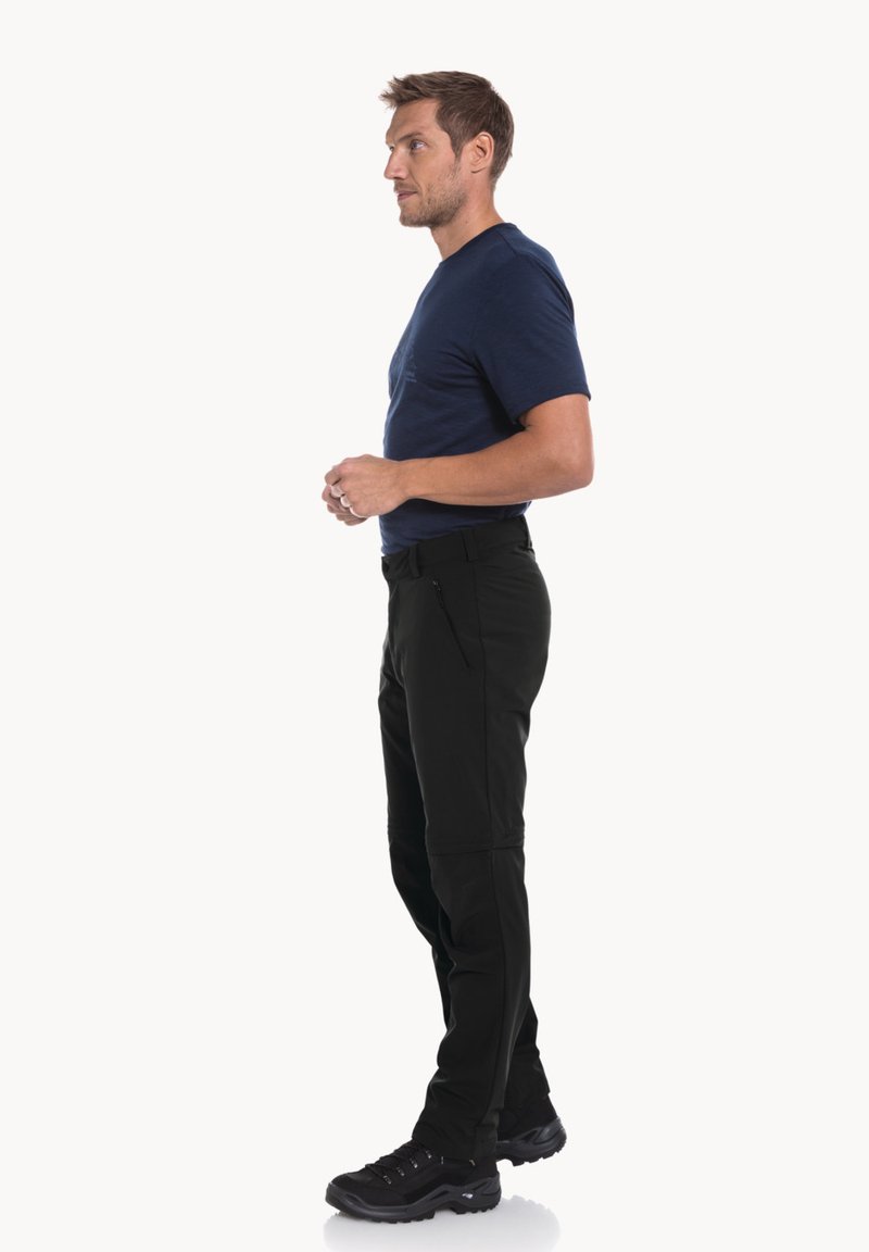 Pantalons softshell noirs avec une coupe slim et des poches latérales zippées, associés à une chemise bleue à manches courtes et des chaussures de sport noires.