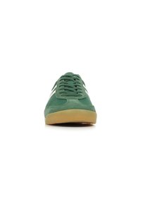 Sneaker verde in suede con dettagli bianchi, caratterizzata da una punta arrotondata e una suola in gomma. Design con lacci e superficie testurizzata per una migliore aderenza.
