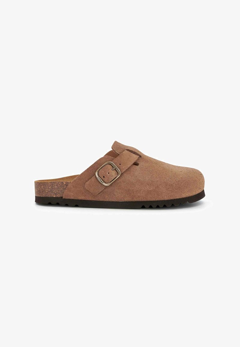 Sabot en suede brun avec détail de boucle, bout arrondi et semelle en caoutchouc texturé. Semelle intermédiaire en liège pour le confort, design bas.