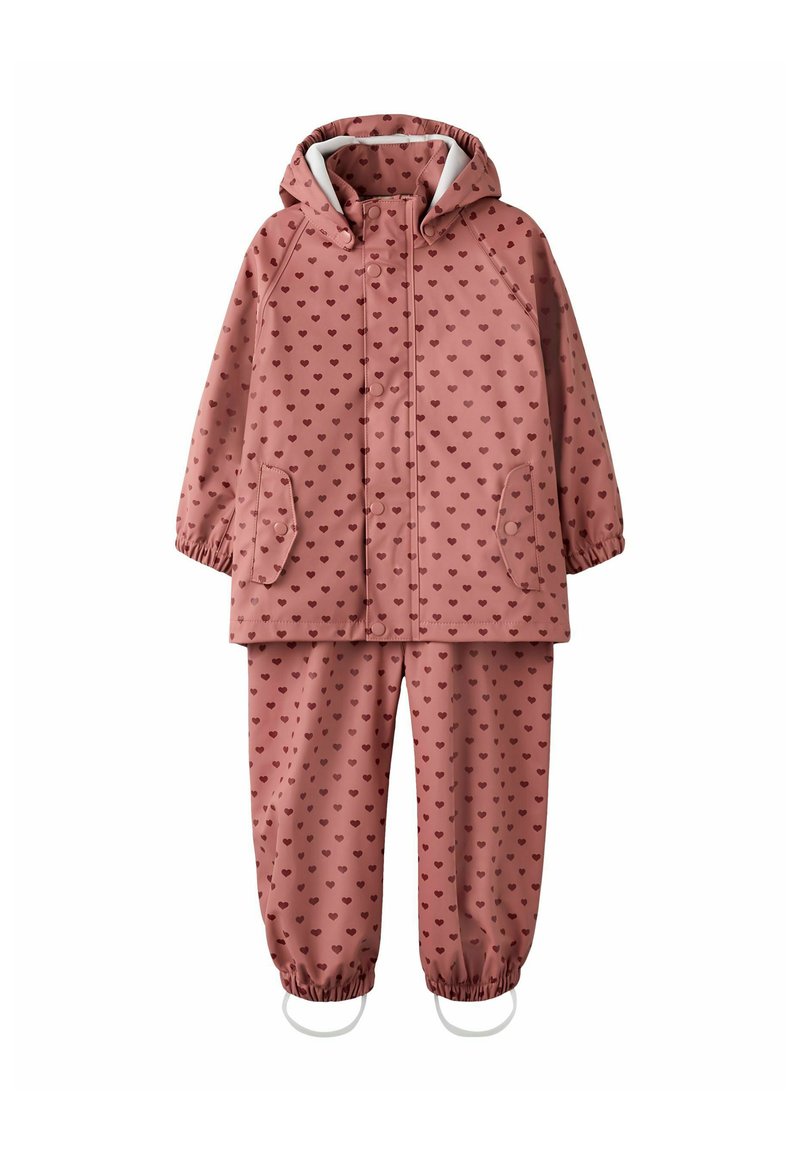 Combinaison de pluie rose imperméable avec de petits motifs en forme de cœur, comprenant une capuche, des poignets élastiques et un fermoir à pressions sur la veste et le pantalon.