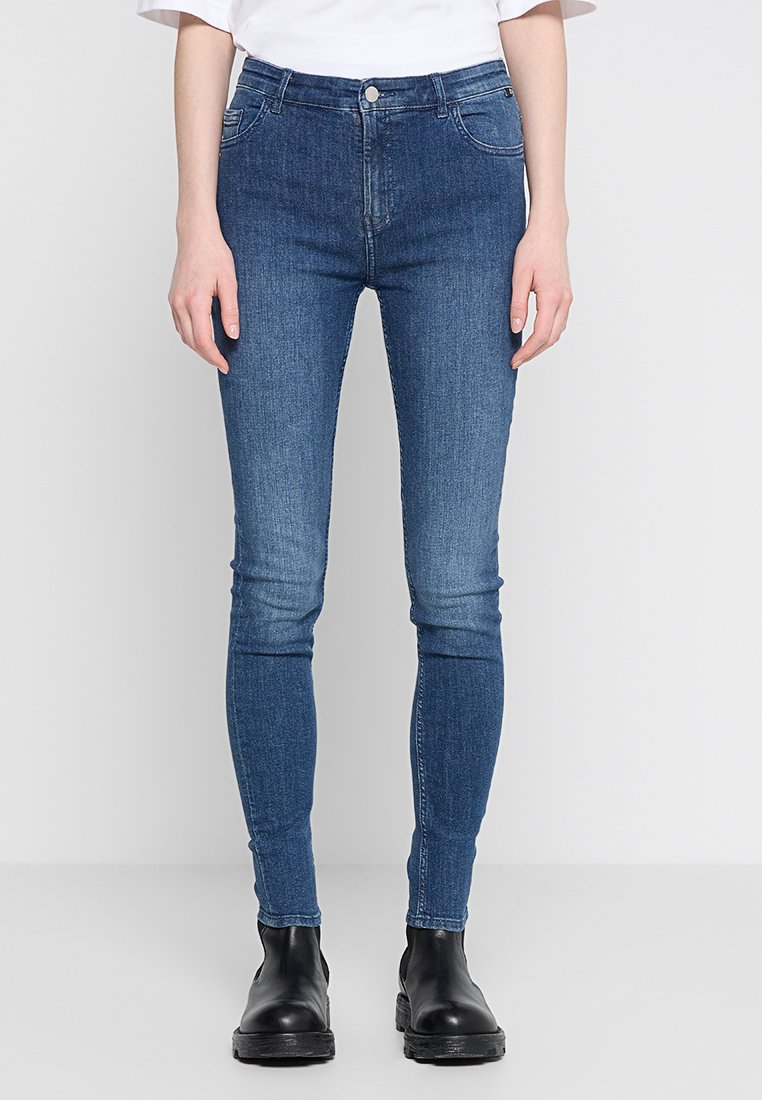 Cienkie dżinsy w ciemnoniebieskim kolorze, z klasycznym pięciopocketowym designem, subtelnym wyblaknięciem i pewnym zapięciem na guziki w pasie.