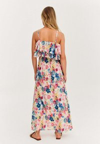 Maxi sukienka w kwiatowy wzór w odcieniach różu, niebieskiego i zielonego; posiada falbaniaste warstwy, cienkie ramiączka oraz dopasowaną talię.
