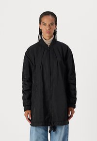 Schwarze Nylon-Bomberjacke mit Reißverschluss, geripptem Kragen und elastischen Bündchen. Verfügt über einen Kordelzugsaum und Seitentaschen.